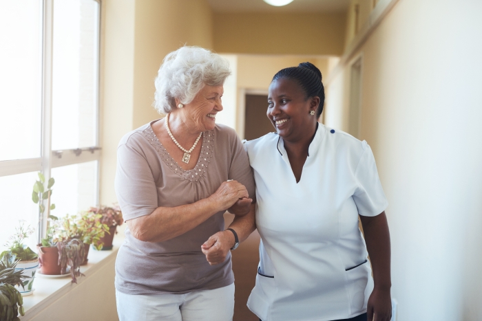 Photo shows a woman being helped to walk by a caregiver.jpeg