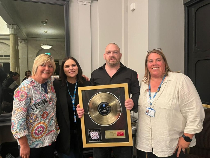 one of the group receiving their gold record as recognition for their contribution to the project.jpg